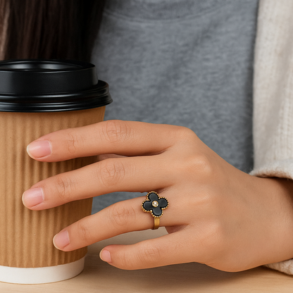 Hand holding a coffee cup with a decorative ring on a neutral background