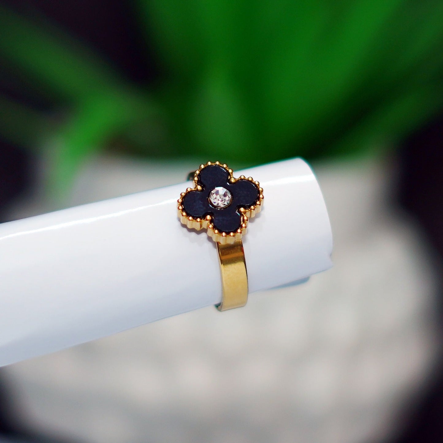 Gold ring with a black gemstone on a white surface with a blurred green background